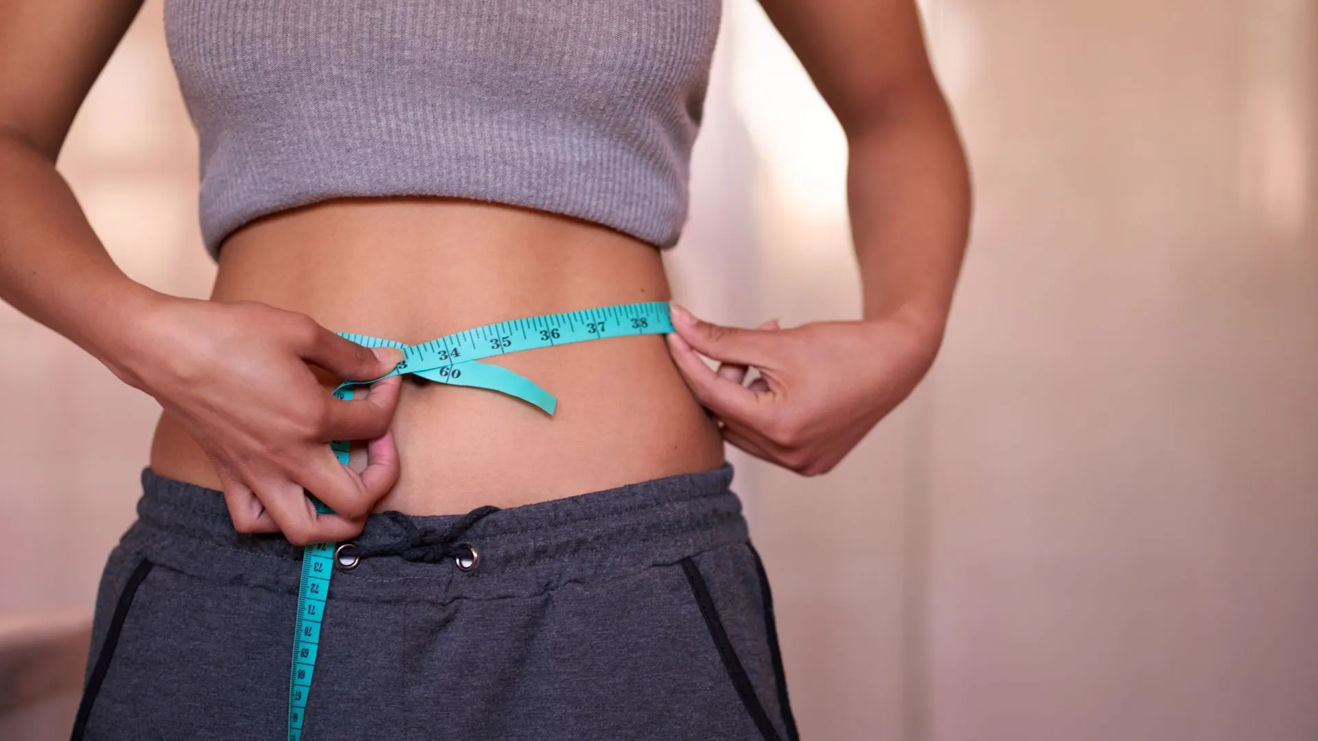 Woman measuring her waist to track fat reduction and body sculpting progress near White Marsh, Maryland.