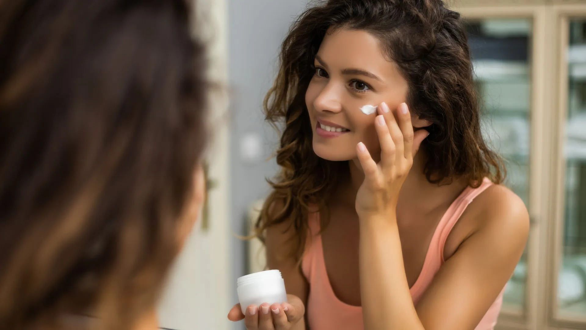 Woman applying skincare cream as part of a skin cycling routine with PCA Skin support in Timonium, Maryland.