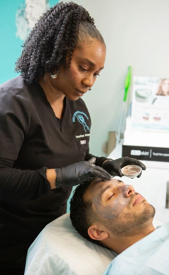 A skincare professional performing a facial treatment on a male client.