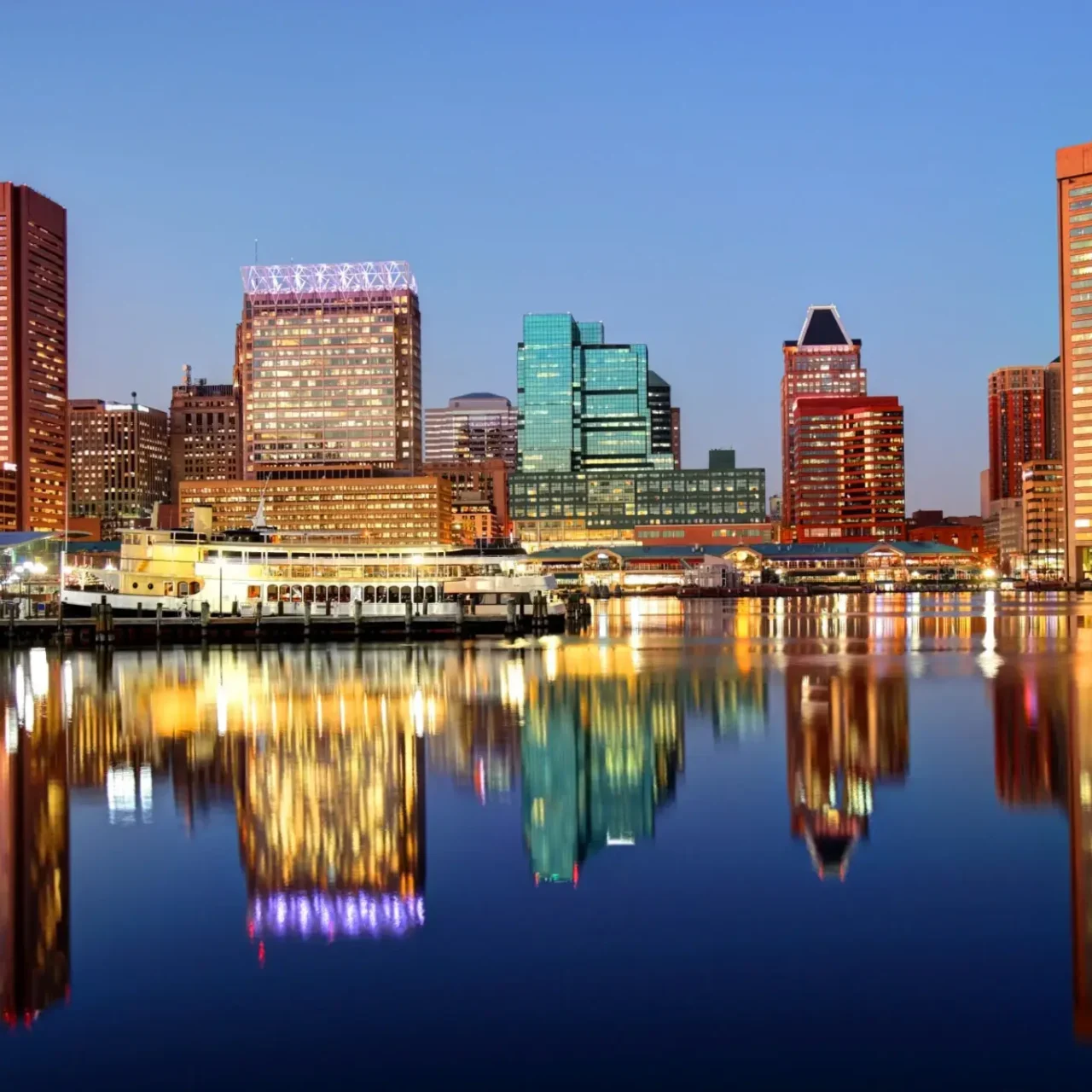 City skyline reflected on calm water at dusk.