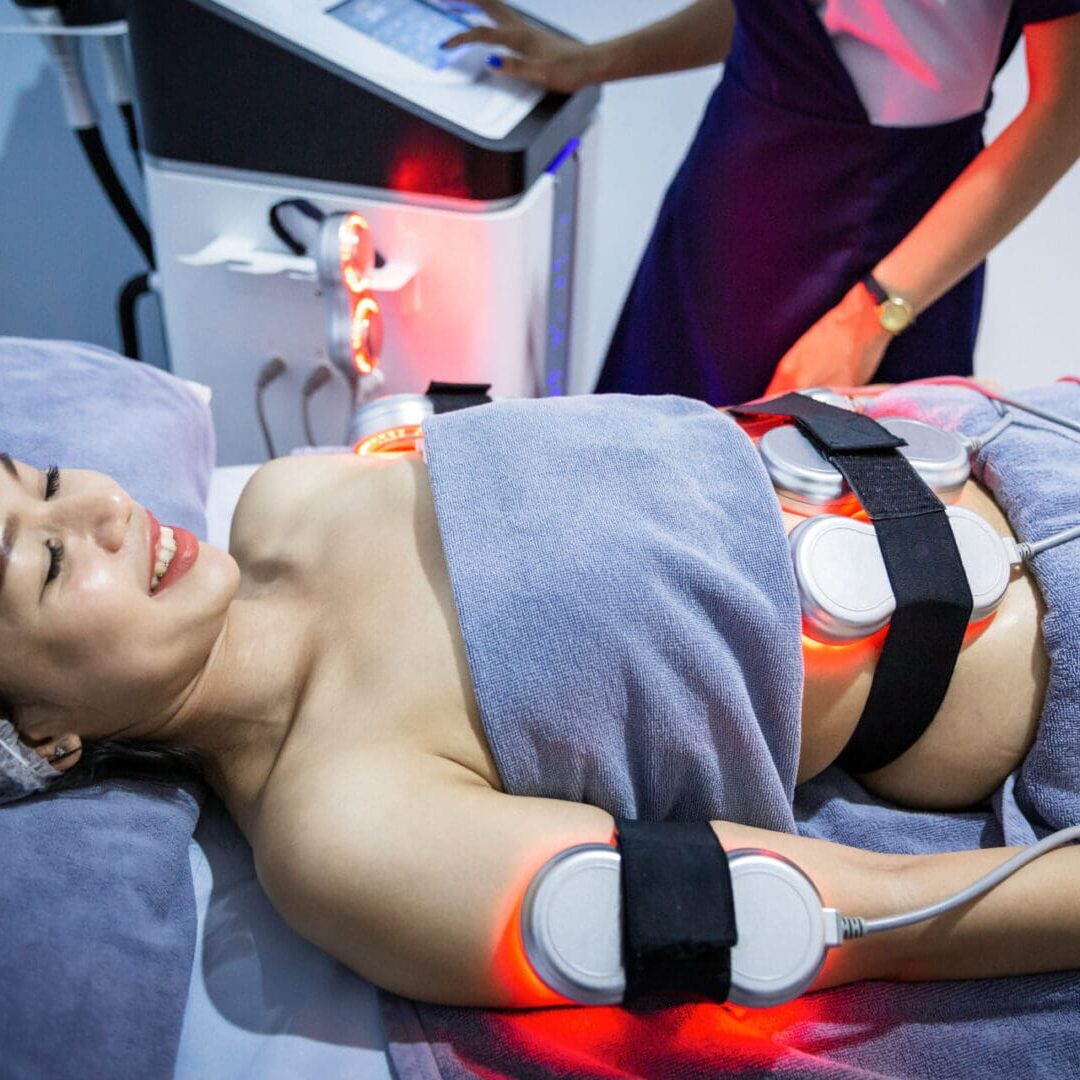 Woman receiving body contouring treatment with LED light therapy.