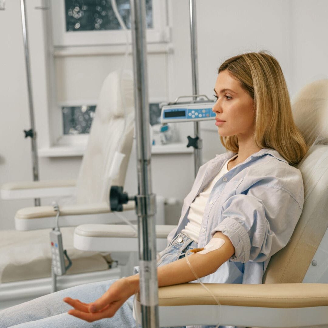 A woman receiving intravenous treatment in a medical setting.