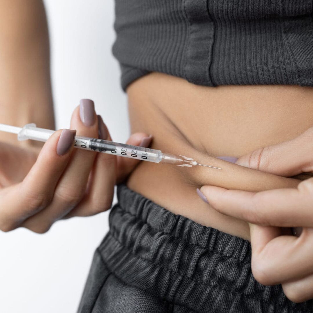 Person injecting insulin into their abdomen.