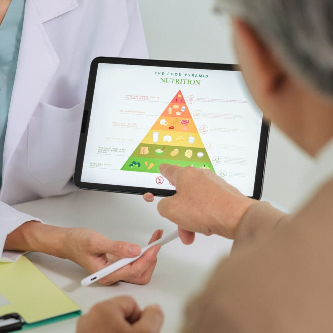 Person pointing at a nutrition pyramid on a tablet during a consultation.