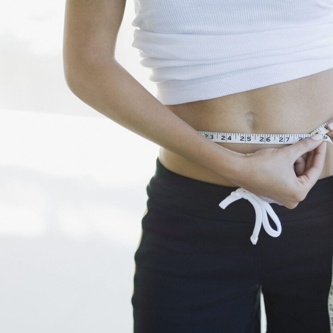 Woman measuring her waist with a tape measure.