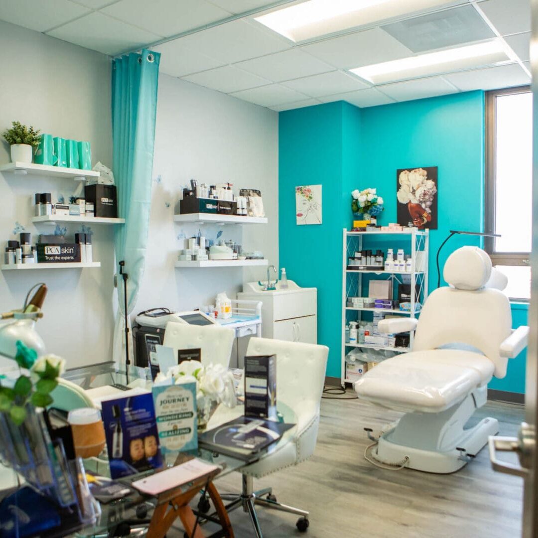 Bright, organized beauty clinic room with white treatment chair and teal walls.
