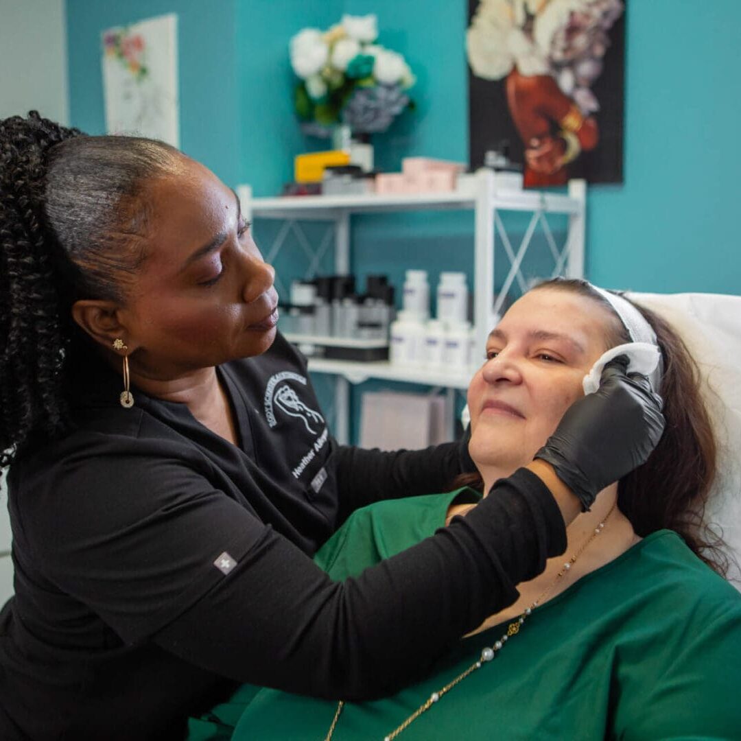 A beautician gently treats a client's face in a cozy spa.