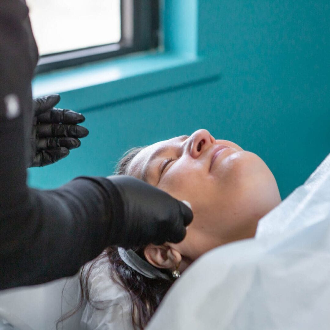 A woman receiving a cosmetic facial treatment in a spa.
