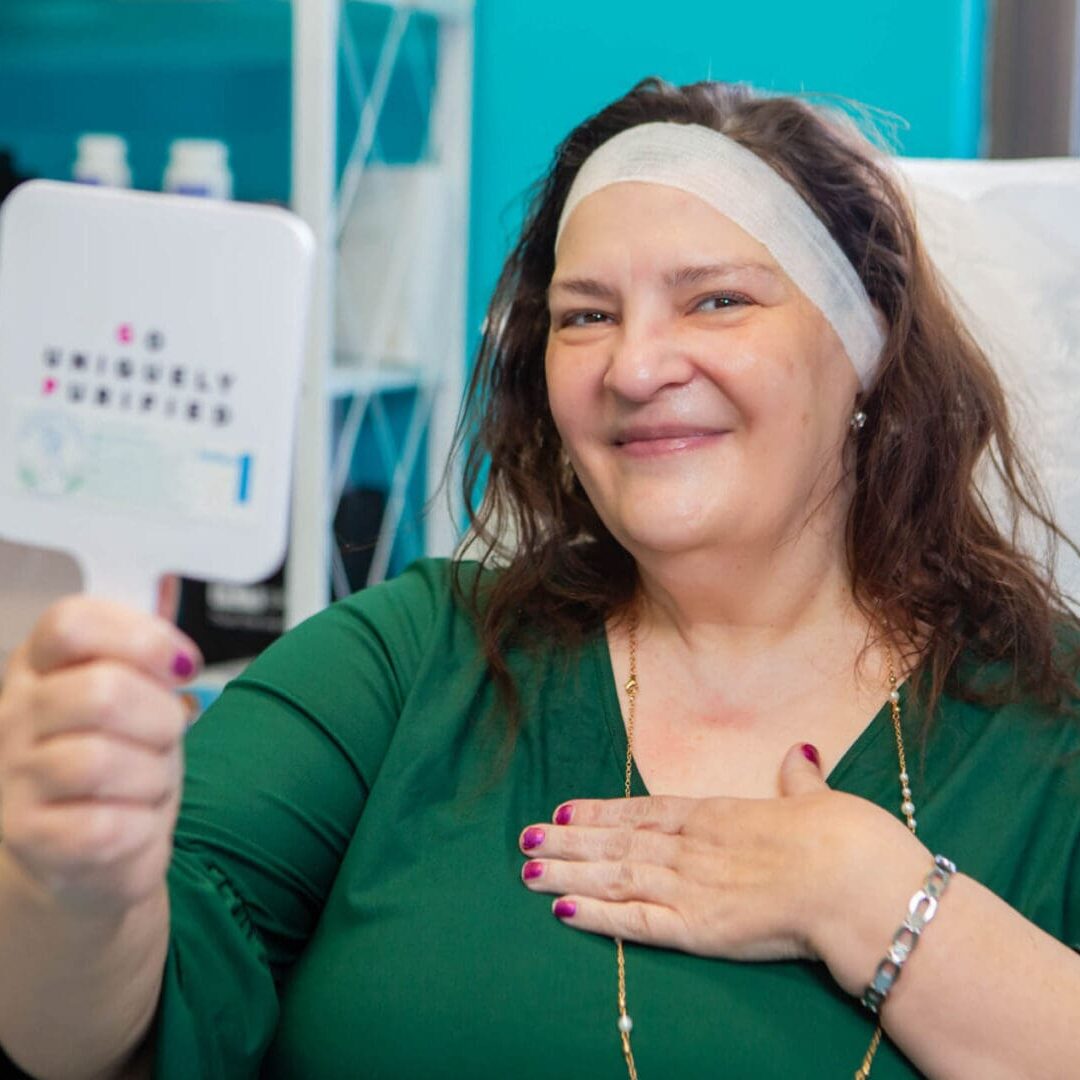 Smiling woman holding an eye chart mirror during an eye exam.