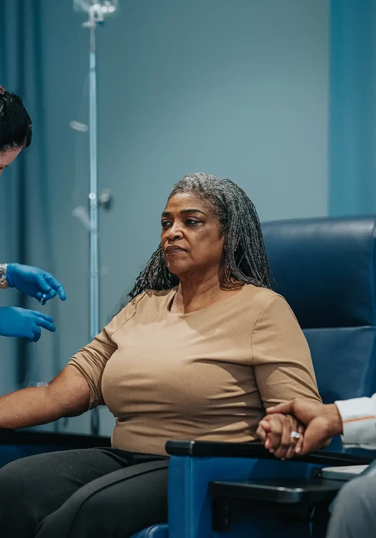 A woman donating blood while medical staff assist her.