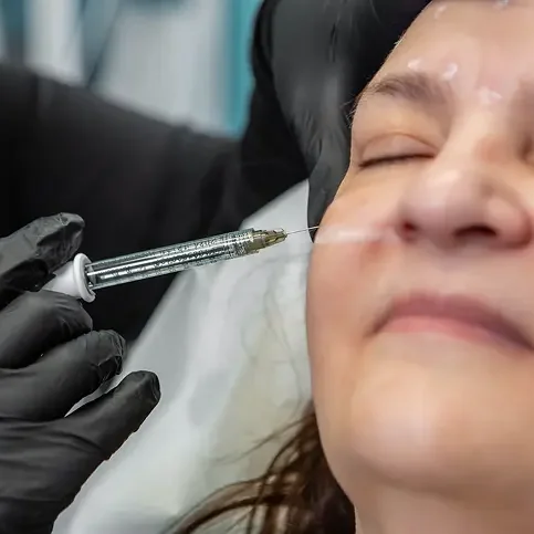 A woman receiving a cosmetic injection on her face.