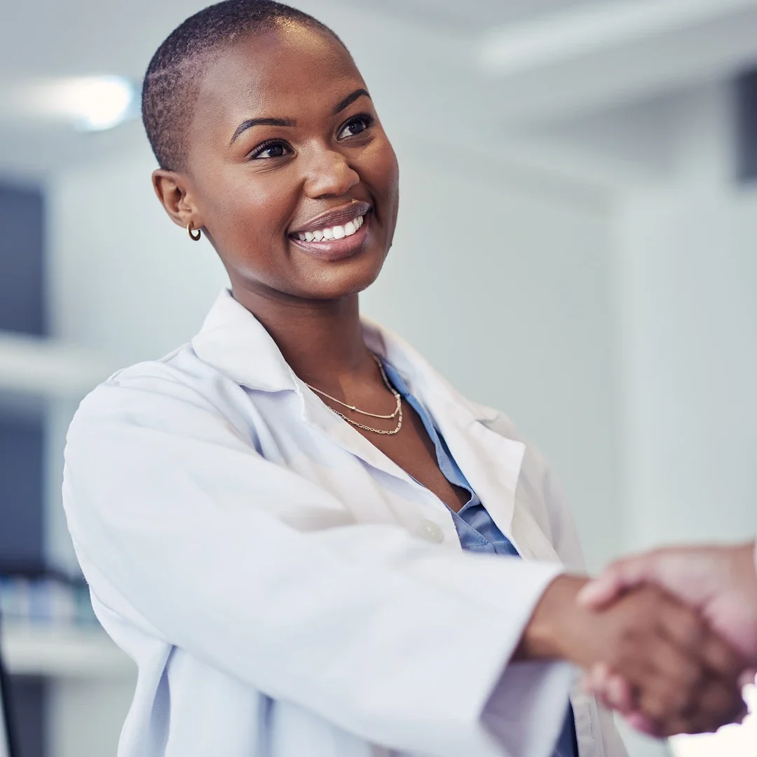 Smiling female doctor shaking hands in a professional setting.
