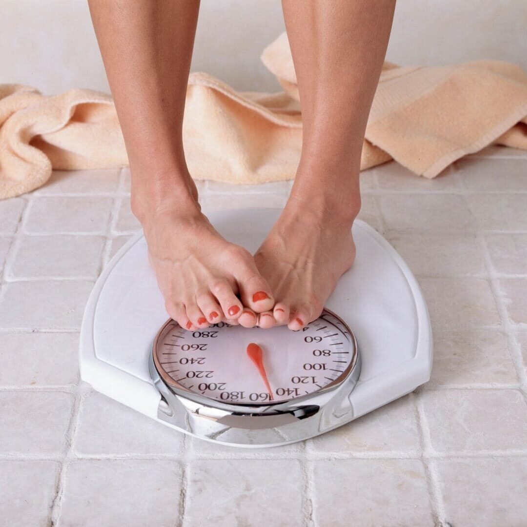 Person standing on a mechanical bathroom scale checking weight.